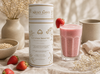 Milkly Wave lactation smoothie container with a glass of pink smoothie and strawberries on a neutral background