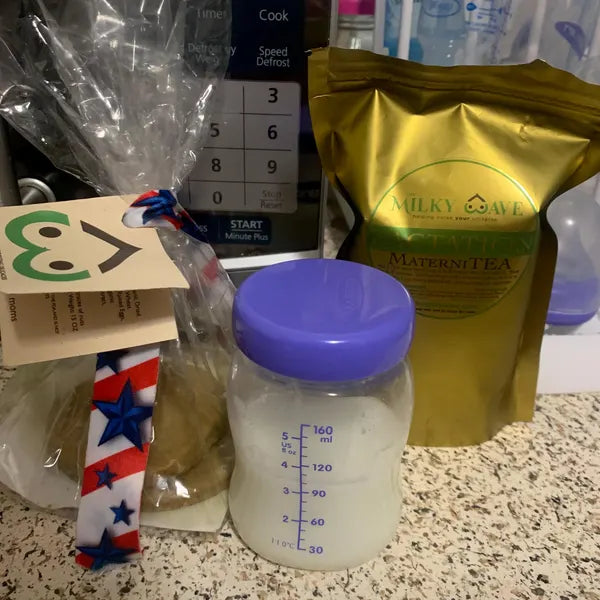 The Milky Wave Maternitea pouch beside a baby bottle and nursing supplies on a kitchen counter